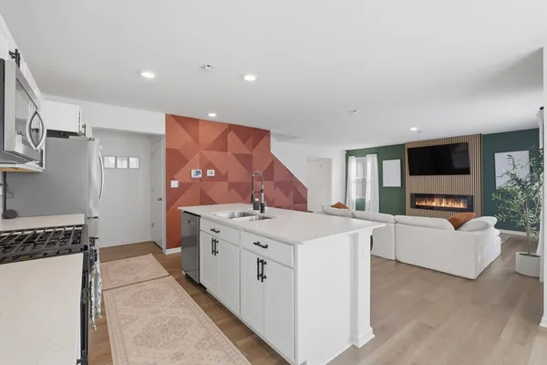 a living room with stainless steel appliances furniture a flat screen tv and a view of kitchen