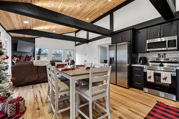 a kitchen with stainless steel appliances kitchen island granite countertop a table chairs sink and cabinets