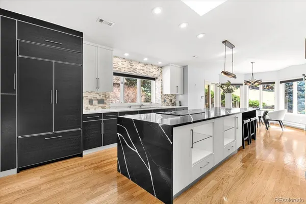 a kitchen with stainless steel appliances granite countertop a sink a counter space and wooden floor