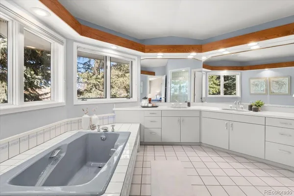 a large white bathroom with a large window sink and cabinets
