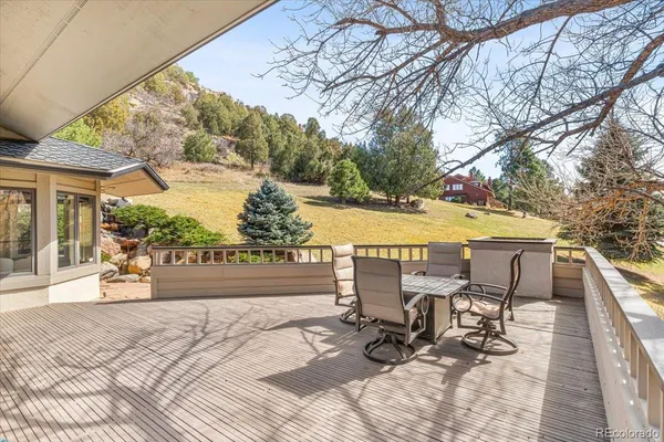 a view of a patio with table and chairs under an umbrella with large trees