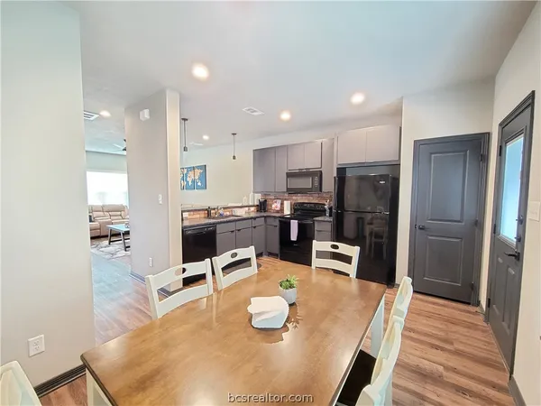 a kitchen with stainless steel appliances wooden floor dining table and chairs
