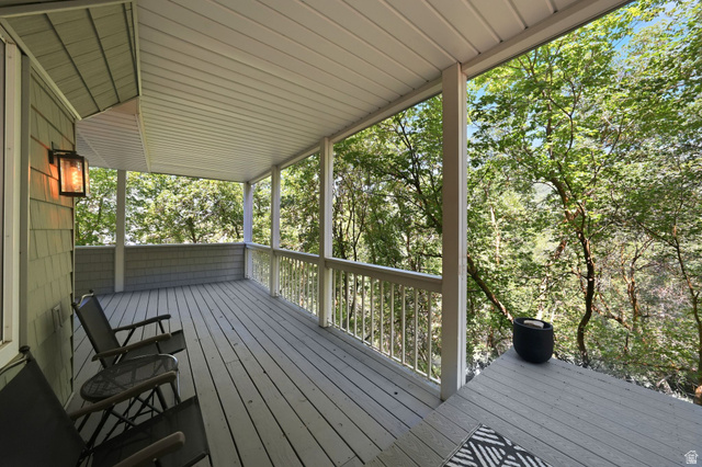 1979 Cave Hollow Way Bountiful, UT 84010 - Photo 42 of 59 Expansive covered porch featuring wood flooring, white railings, and a shingled exterior wall with an exterior light fixture