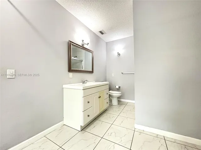 a spacious bathroom with a double vanity sink a mirror and a toilet