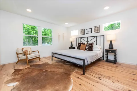 a bedroom with a bed lamp and a large window with wooden floor