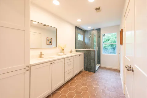 a spacious bathroom with a double vanity sink a mirror and a