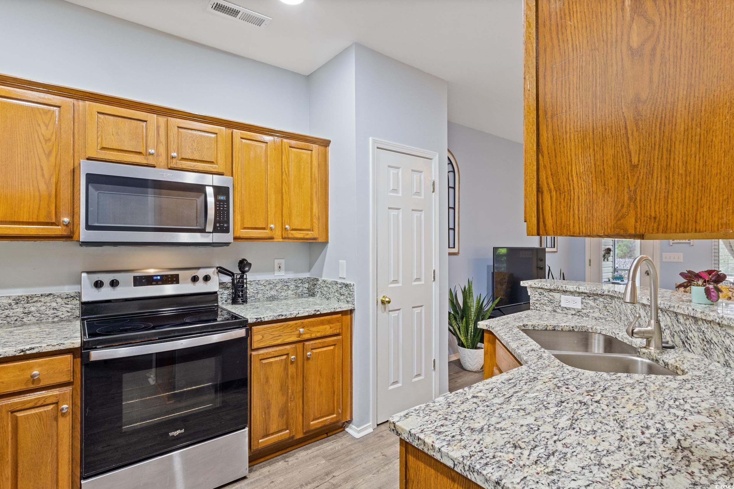 140 Olde Towne Way, Unit 2 Myrtle Beach, SC 29588 - Photo 11 of 40 Kitchen featuring stainless steel appliances, brown cabinetry, light stone countertops, and light wood-style floors