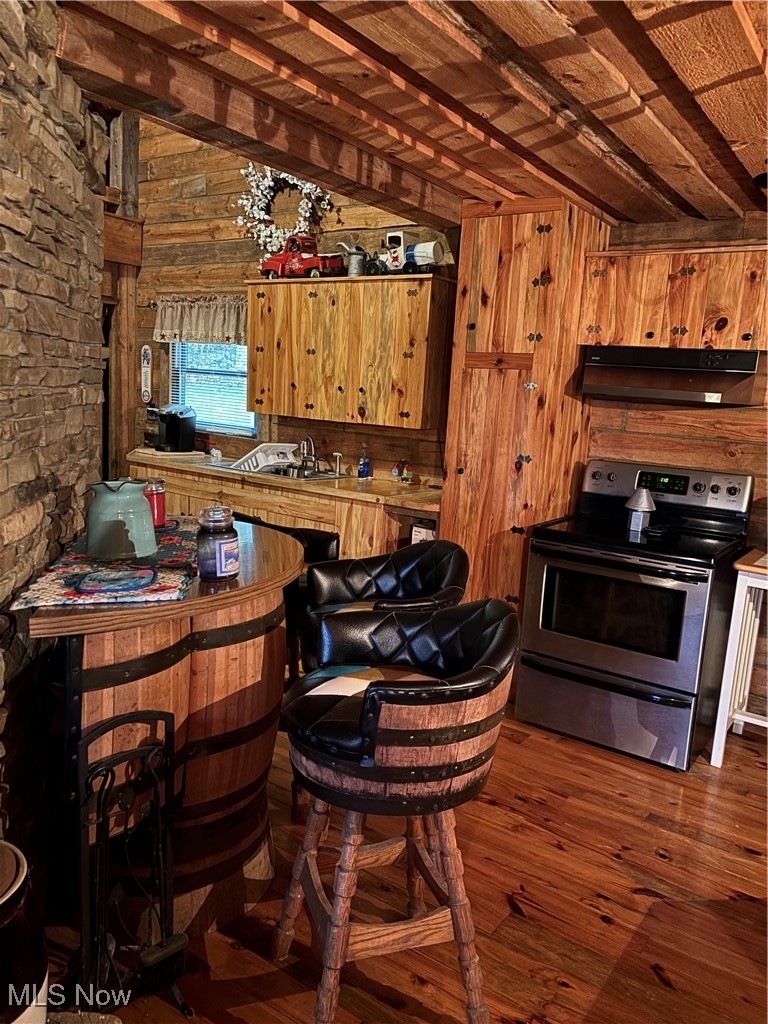 55249 Jim Ball Road Senecaville, OH 43780 - Photo 10 of 14 Kitchen featuring beam ceiling, range, dark wood-style flooring, wooden walls, and extractor fan