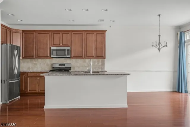 a kitchen with kitchen island granite countertop a stove top oven a sink and dishwasher