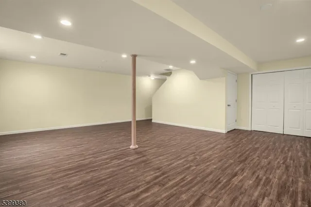 a view of an empty room with wooden floor and a closet