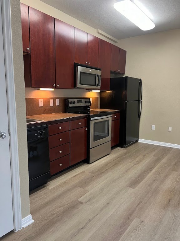 2505 San Gabriel Street, Unit 101 Austin, TX 78705 - Photo 5 of 9 a kitchen with stainless steel appliances granite countertop wooden cabinets a stove top oven a sink and dishwasher