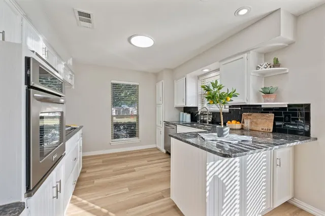a kitchen with stainless steel appliances granite countertop a stove a sink and a refrigerator