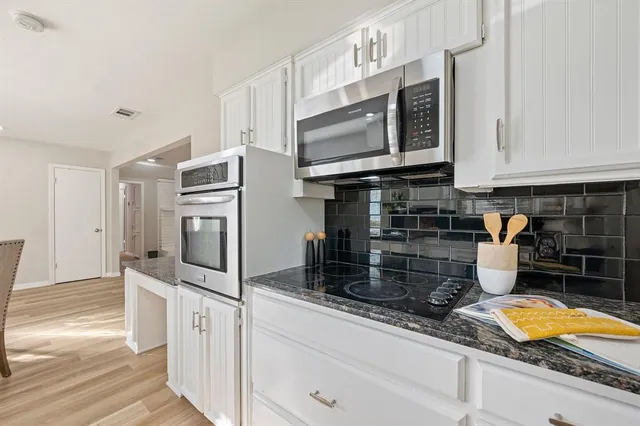 a kitchen with stainless steel appliances granite countertop a stove a microwave and a sink