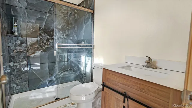 a bathroom with a granite countertop sink toilet and shower