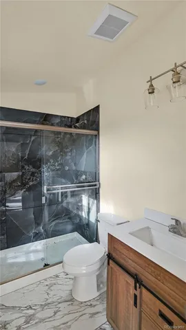 a bathroom with a granite countertop sink a toilet a vanity and shower