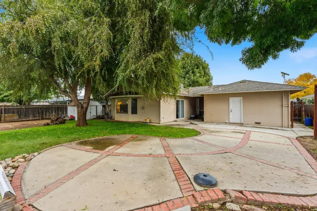 a view of a house with a yard and large tree