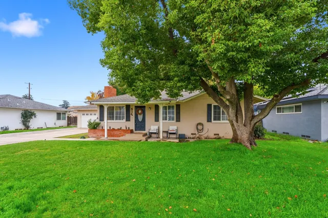 a front view of a house with a garden and trees