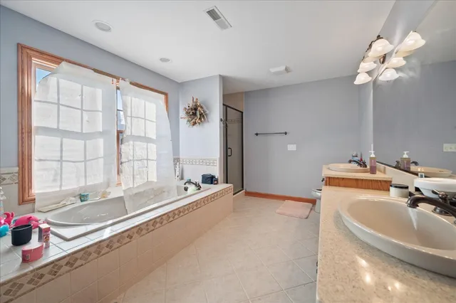 a bathroom with a tub a sink double vanity and a large mirror