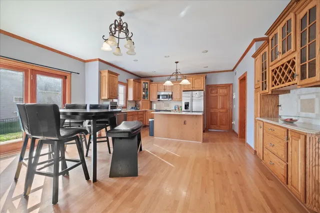 a kitchen with stainless steel appliances granite countertop a stove top oven a refrigerator a dining table and chairs with wooden floor