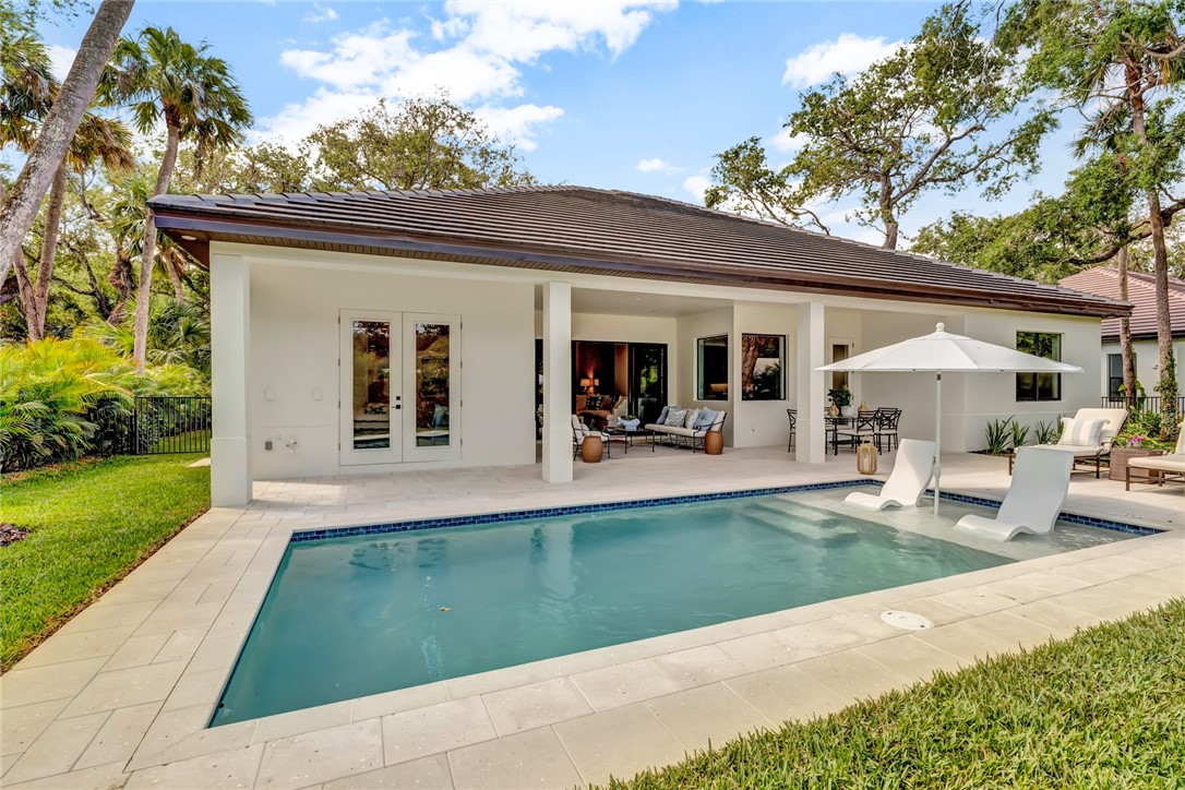 325 Holly Road Vero Beach, FL 32963 - Photo 23 of 25 a view of a patio with table and chairs potted plants and a large tree
