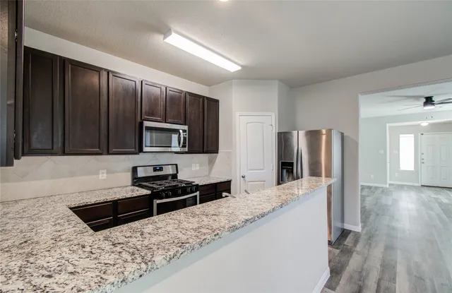 a kitchen with stainless steel appliances granite countertop a refrigerator stove and sink