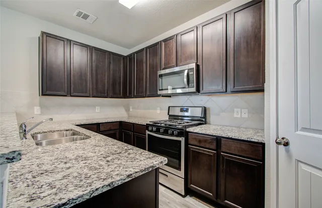 a kitchen with granite countertop wooden cabinets and a stove top oven