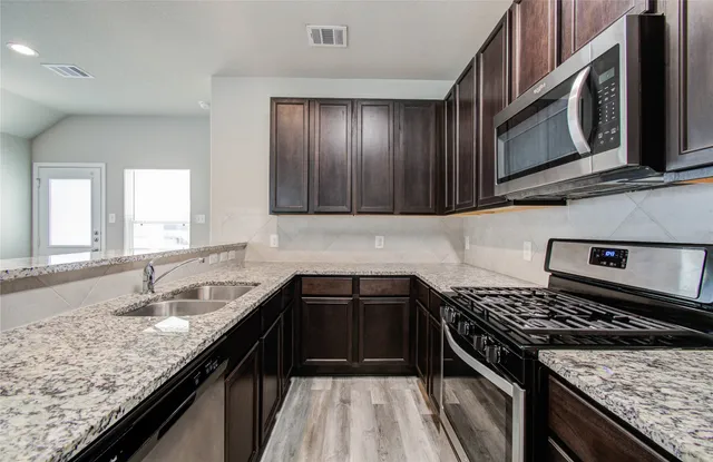 a kitchen with granite countertop stainless steel appliances sink microwave and stove