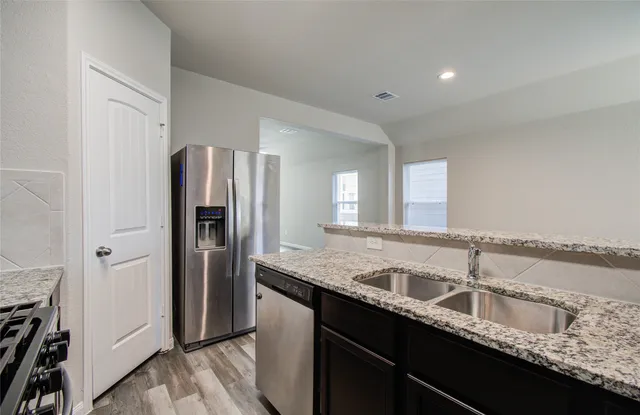 a kitchen with granite countertop a sink and a refrigerator