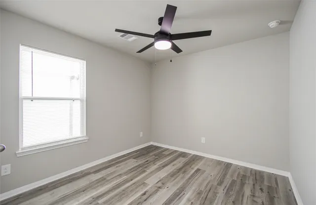 an empty room with a window and a ceiling fan