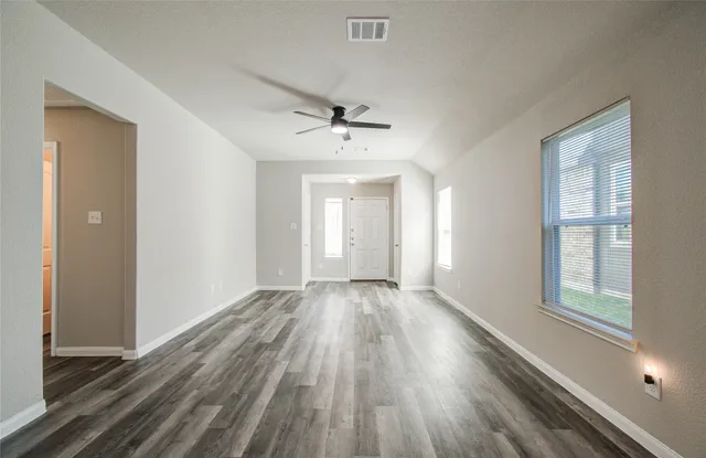 a view of an empty room with a window and wooden floor