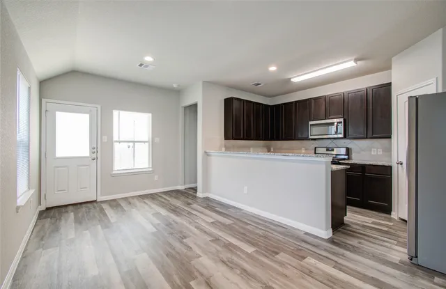 a view of kitchen with granite countertop cabinets and refrigerator