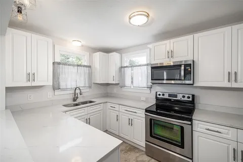 a kitchen with white cabinets stainless steel appliances and sink