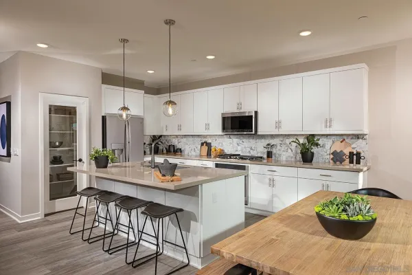 a kitchen with stainless steel appliances kitchen island granite countertop a stove a sink dishwasher a dining table and chairs with wooden floor