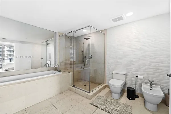 a spacious bathroom with a granite countertop sink a toilet a mirror and shower