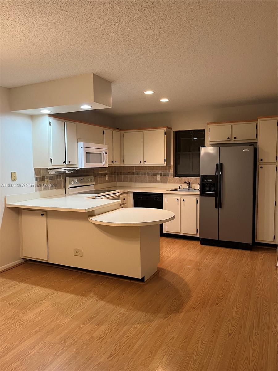7657 Courtyard Run West, Unit 7657 Boca Raton, FL 33433 - Photo 22 of 36 a large kitchen with stainless steel appliances granite countertop a stove a sink and a refrigerator