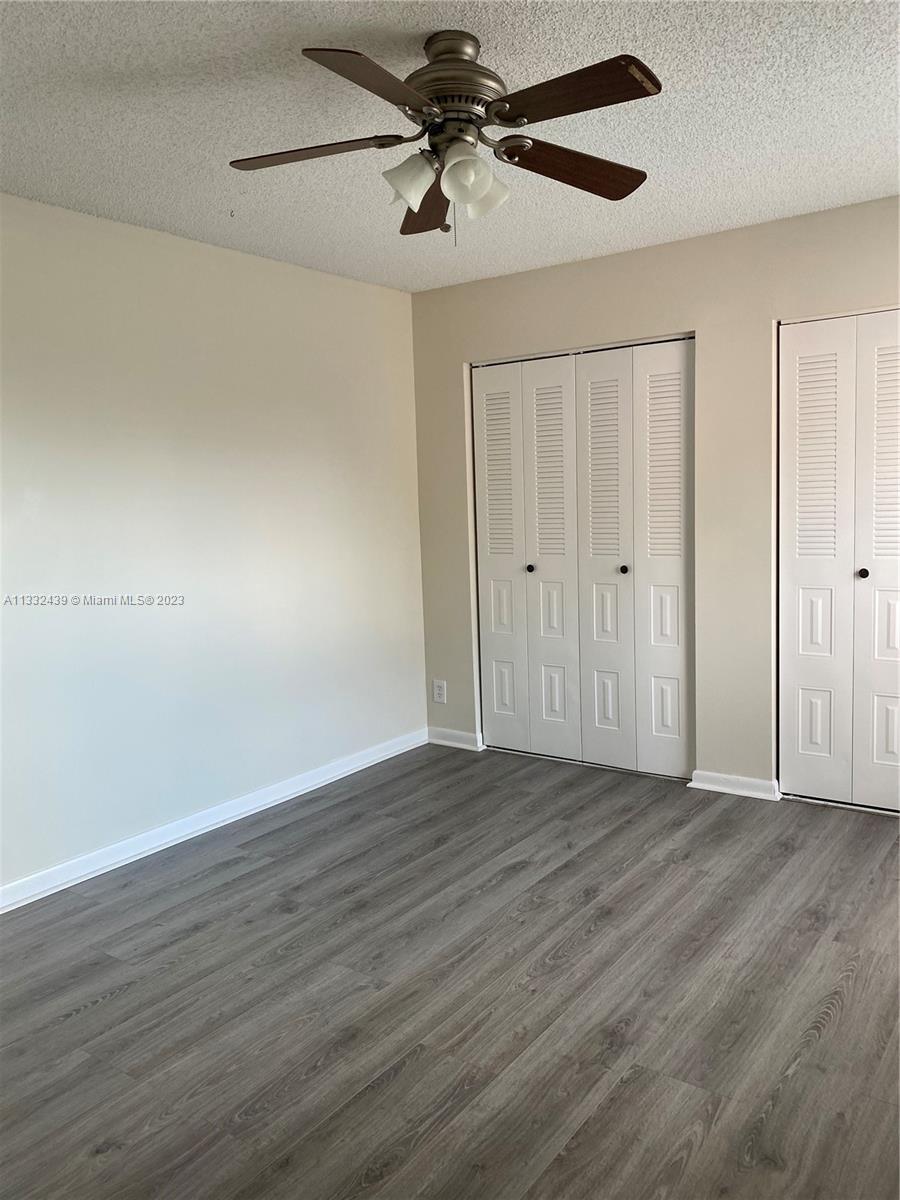 7657 Courtyard Run West, Unit 7657 Boca Raton, FL 33433 - Photo 23 of 36 a view of an empty room and window a ceiling fan and wooden floor