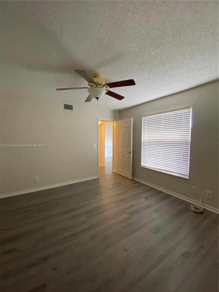 7657 Courtyard Run West, Unit 7657 Boca Raton, FL 33433 - Photo 25 of 36 a view of an empty room with a window and wooden floor