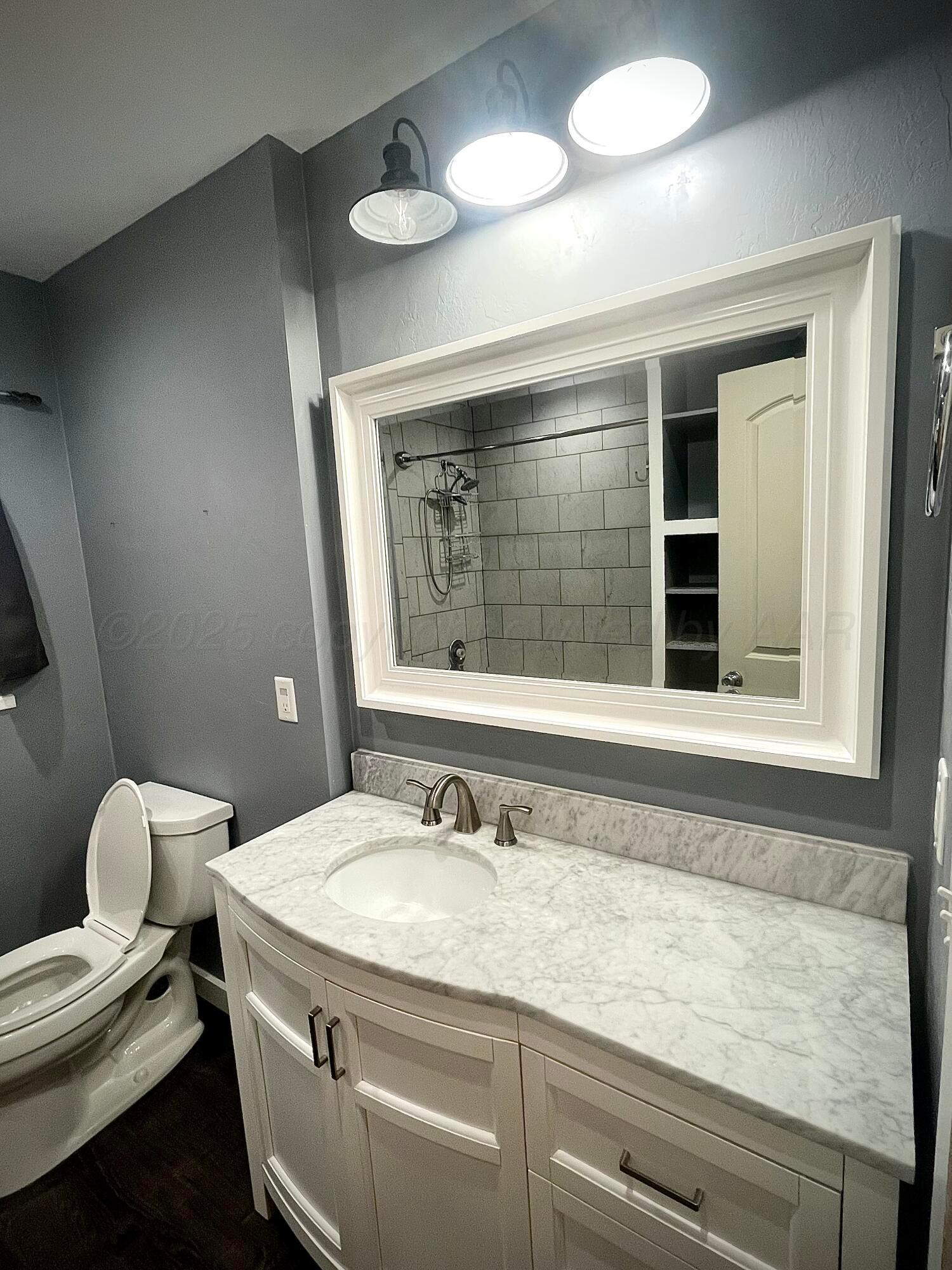 5116 Crockett Street Amarillo, TX 79110 - Photo 12 of 23 a bathroom with a granite countertop sink a toilet and a mirror