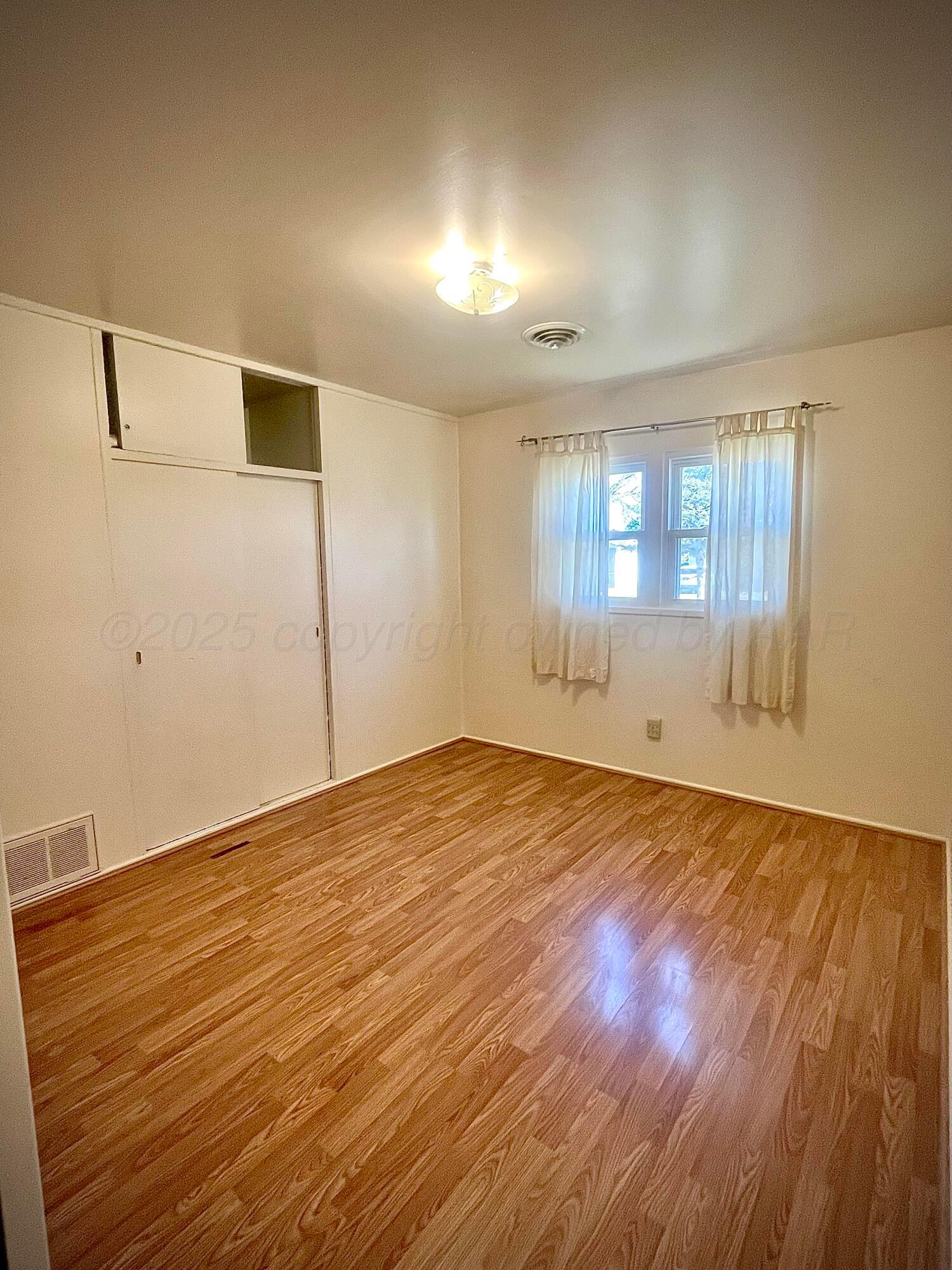 5116 Crockett Street Amarillo, TX 79110 - Photo 13 of 23 an empty room with wooden floor and windows