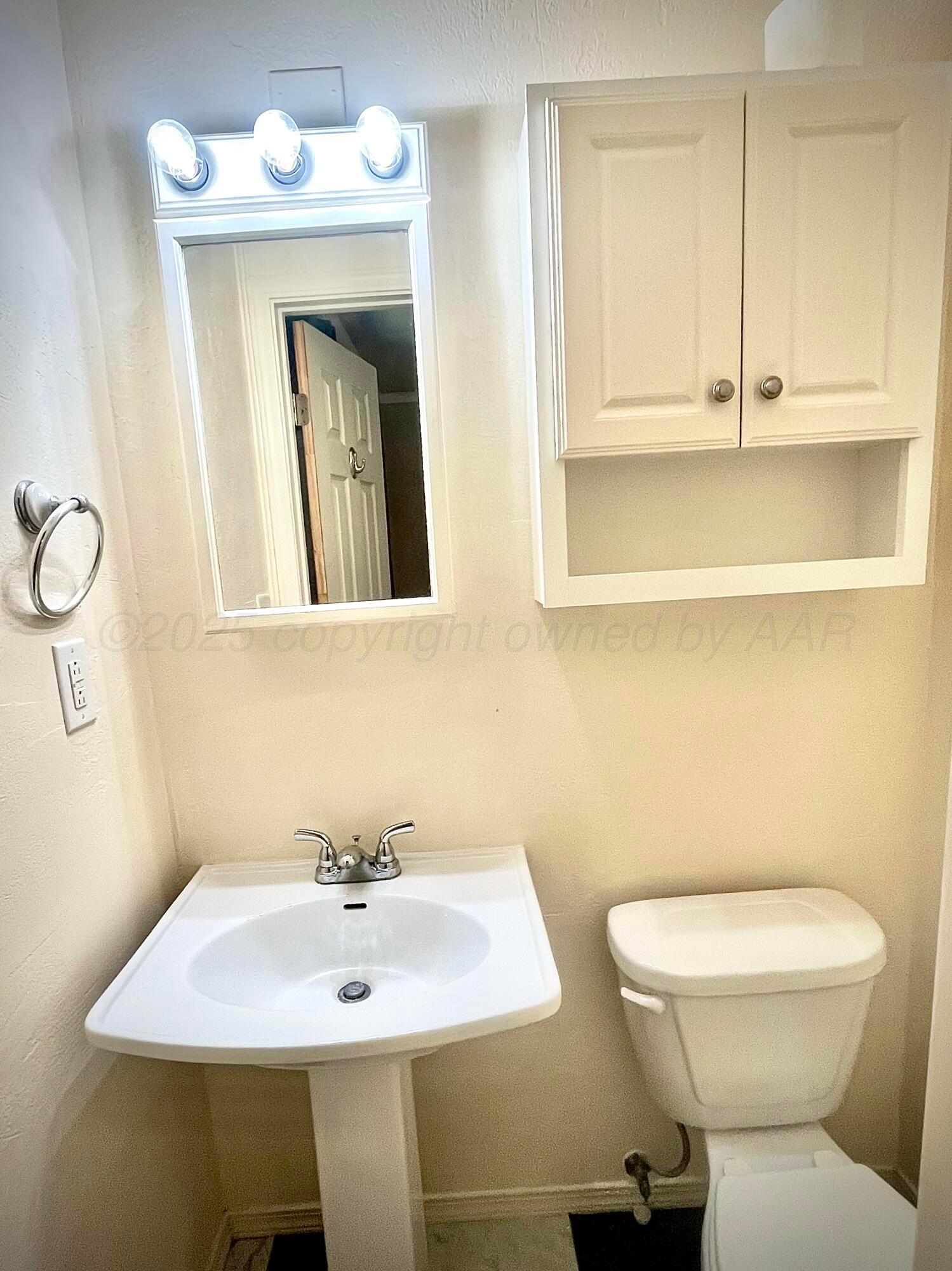 5116 Crockett Street Amarillo, TX 79110 - Photo 16 of 23 a bathroom with a toilet sink and mirror