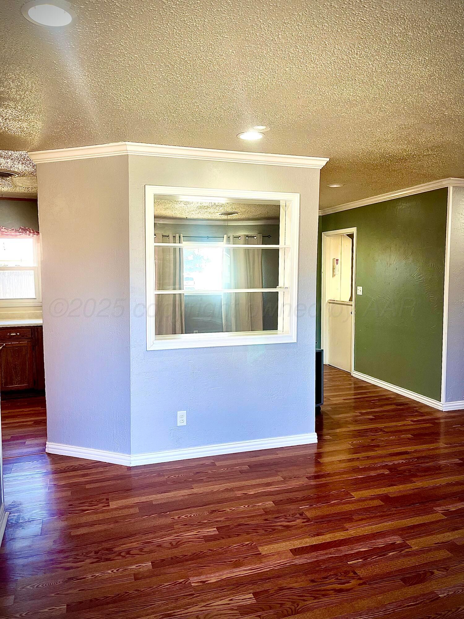 5116 Crockett Street Amarillo, TX 79110 - Photo 5 of 23 a view of an empty room with wooden floor and a window