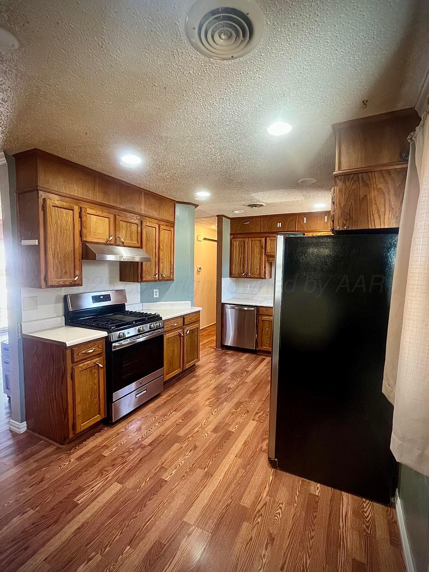 5116 Crockett Street Amarillo, TX 79110 - Photo 7 of 23 a large kitchen with stainless steel appliances wooden cabinets and a counter top space