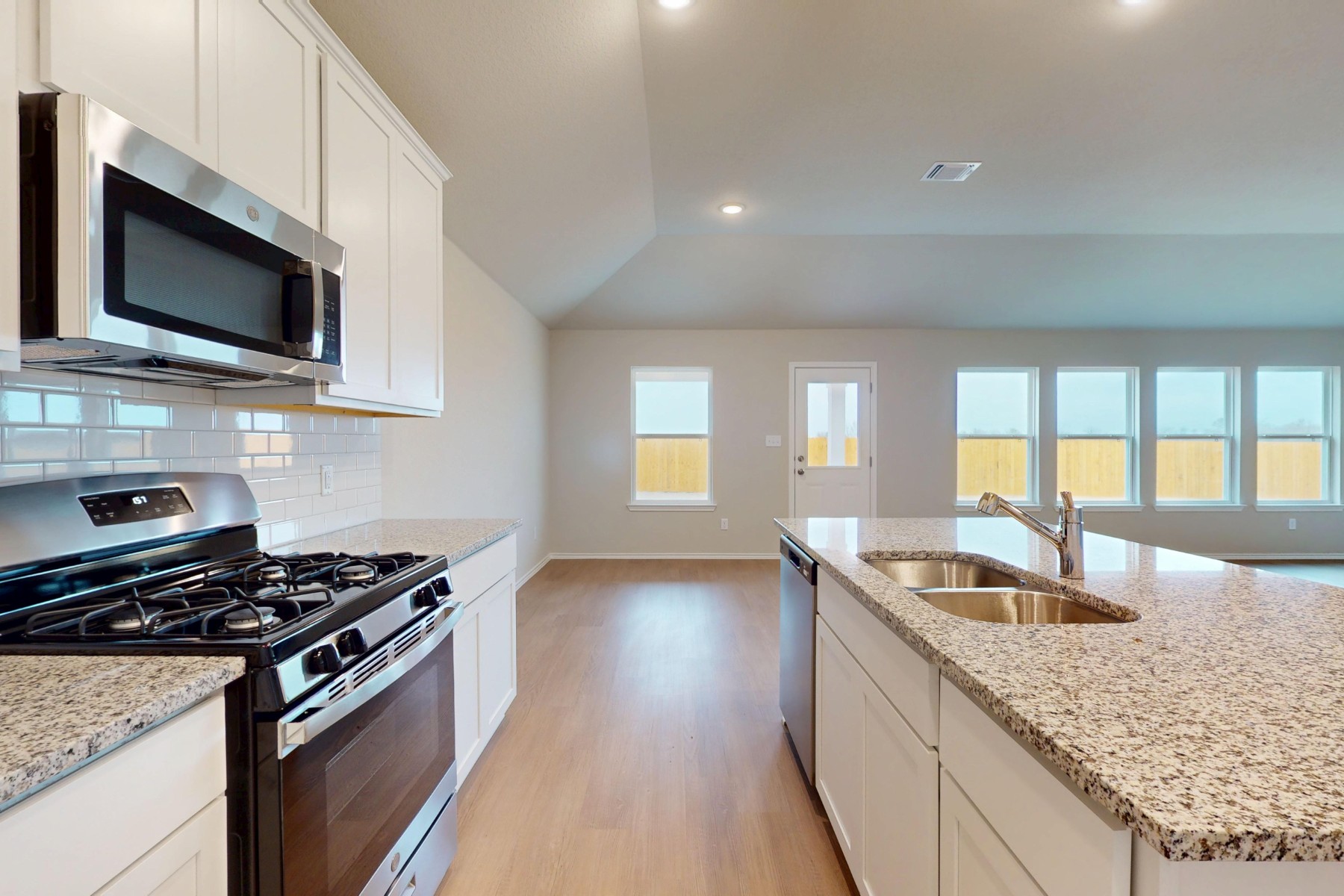 20017 Schatz Way Manor, TX 78653 - Photo 6 of 34 a kitchen with granite countertop stainless steel appliances a sink stove top oven and microwave