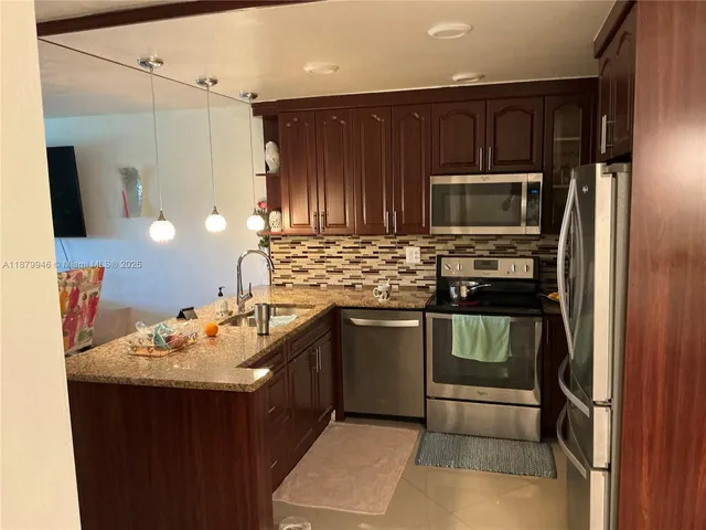 a kitchen with kitchen island granite countertop a sink stove and refrigerator