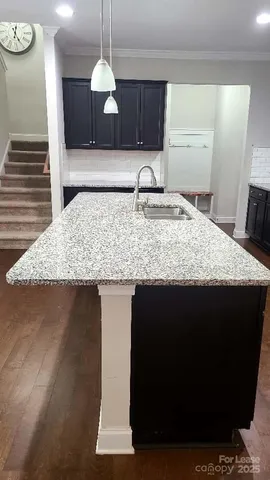 a kitchen with a sink granite counter tops and a wooden floor