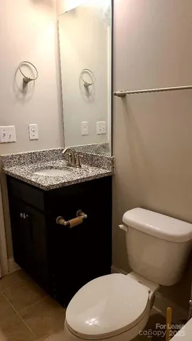 a bathroom with a granite countertop toilet sink and mirror