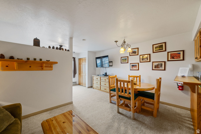 150 Ridgeview Street, Unit 117 Brian Head, UT 84719 - Photo 17 of 20 Dining room with suspended lighting, light colored carpet, and a textured ceiling