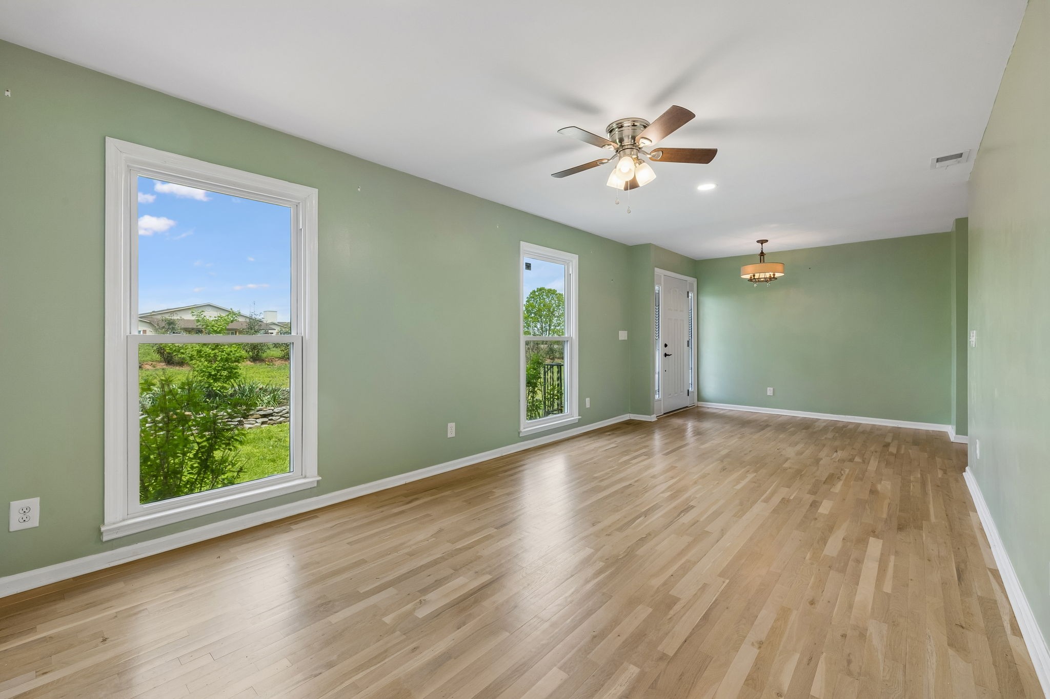 771 Mt Pleasant Road Kingston Springs, TN 37082 - Photo 6 of 31 an empty room with wooden floor chandelier fan and windows