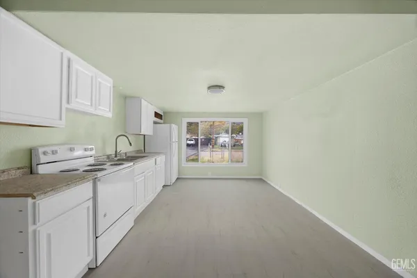 a large white kitchen with stainless steel appliances a sink a stove a chimney and a window