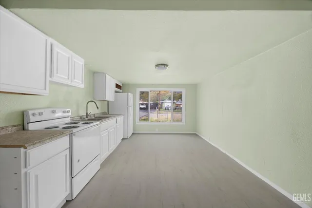 a large white kitchen with stainless steel appliances a sink a stove a chimney and a window